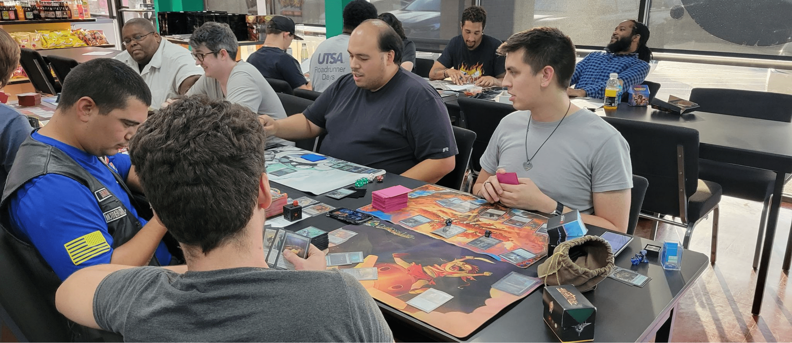 Diverse group playing games members of Dragon's Lair's inclusive gaming community at a Magic event
